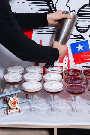 Bartender pouring a New York sour cocktail from the steel shaker to a glass on the bar counterの写真素材
