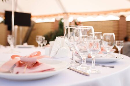 Glasses, forks, knives, plates on a table in restaurant served for dinnerの写真素材