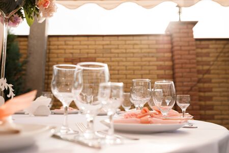 Glasses, forks, knives, plates on a table in restaurant served for dinnerの写真素材