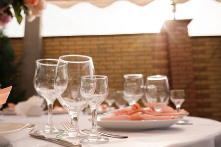 Glasses, forks, knives, plates on a table in restaurant served for dinnerの写真素材