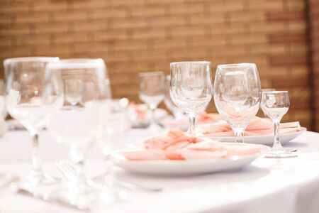 Glasses, forks, knives, plates on a table in restaurant served for dinnerの写真素材