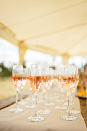 Elegant glasses with champagne standing in a row on serving table during party or celebrationの写真素材