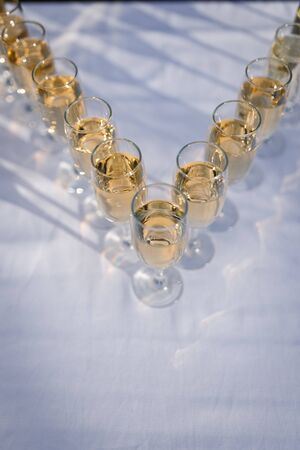 Elegant glasses with champagne standing in a row on serving table during party or celebrationの写真素材