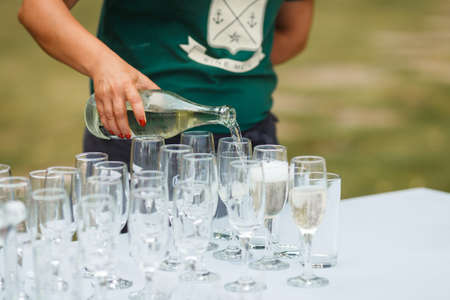 Waiter pours champagne in glasses on the streetの写真素材