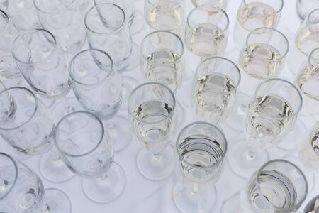Elegant glasses with champagne standing in a row on serving table during party or celebrationの写真素材