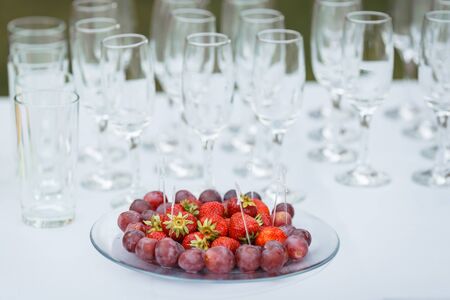 Strawberries and red grapes for wine. Wineglass on the background.の写真素材