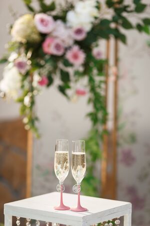 Glasses with champagne on the table for the bride and groom at the engagement ceremonyの写真素材