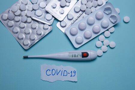 Tablets, pills and thermometer on a blue background. Flu cold concept. Healthcare medical concept. Medicine pill. Emergency medical treatment. Coronavirus medikament concept.の写真素材