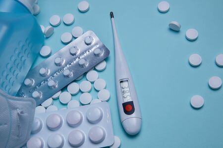 Tablets, pills and thermometer on a blue background. Flu cold concept. Healthcare medical concept. Medicine pill. Emergency medical treatment. Coronavirus medikament concept.の写真素材