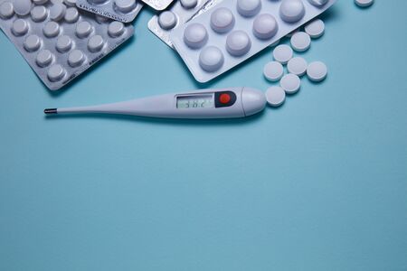 Tablets, pills and thermometer on a blue background. Flu cold concept. Healthcare medical concept. Medicine pill. Emergency medical treatment. Coronavirus medikament concept.の写真素材