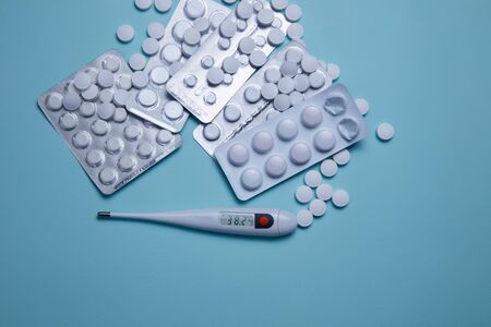 Tablets, pills and thermometer on a blue background. Flu cold concept. Healthcare medical concept. Medicine pill. Emergency medical treatment. Coronavirus medikament concept.の写真素材