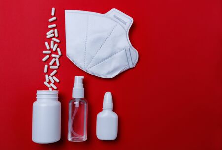 Sanitizer, protective mask and pills on a red background. Concept of medicine. Prevention of coronavirus.の写真素材