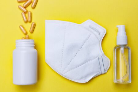Sanitizer, protective mask and pills on a yellow background. Concept of medicine. Prevention of coronavirus.の写真素材