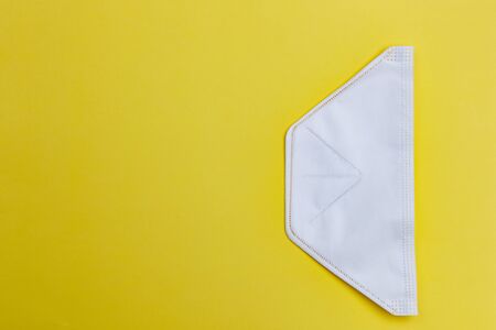 Protective white medical mask close up on yellow background used as protection from coronavirus...