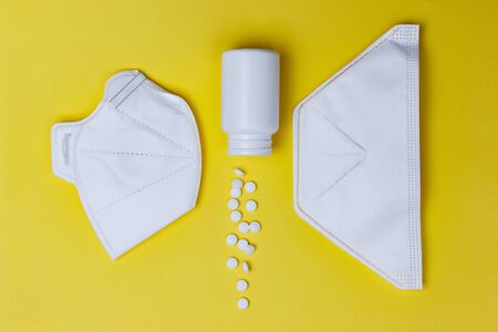 pills and protective masks on a yellow background. Concept of medicine. Prevention of coronavirus.の写真素材