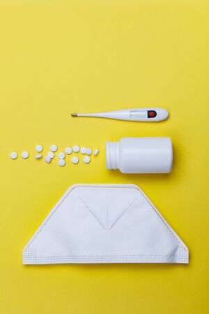 protective mask, thermometer and pills on a yellow background. Concept of medicine. Prevention of coronavirus.の写真素材