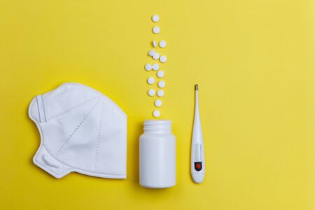 protective mask, thermometer and pills on a yellow background. Concept of medicine. Prevention of coronavirus.の写真素材