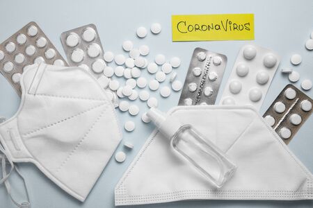 Coronavirus phrase text flat lay on blue background with pills, sanitizer and protective masks. CORONAVIRUS concept.の写真素材