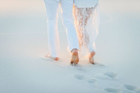 Lovers walk barefoot on the sand in the white desert. Love in the desert newlyweds.の写真素材