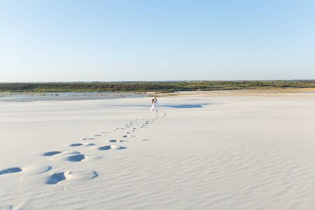 Newlyweds walk barefoot on the sand in the white desert. Love in the desert newlyweds.の写真素材