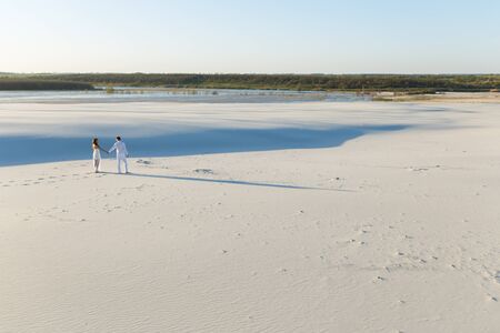 Lovers walk barefoot on the sand in the white desert. Love in the desert newlyweds.の写真素材