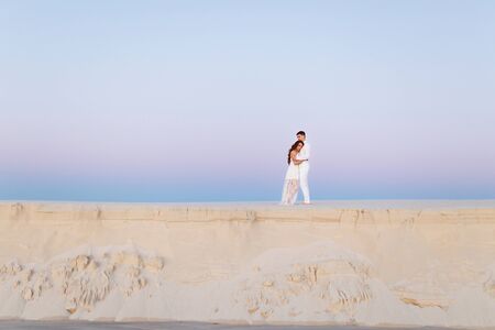 Young couple hugging in a white desert during a romantic honeymoon trip.の写真素材