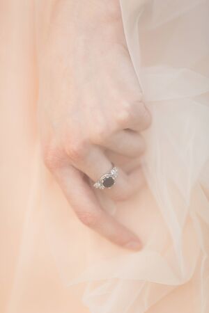 Bride's hand under the long veil with white gold engagement ringの写真素材