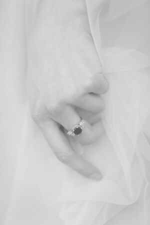 Bride's hand under the long veil with white gold engagement ringの写真素材