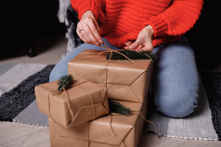 Girl in a red sweater wraps gifts in craft paper for the new year.の写真素材
