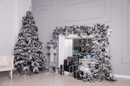 Christmas tree decorated with gifts stands in light interiors with a fireplaceの写真素材