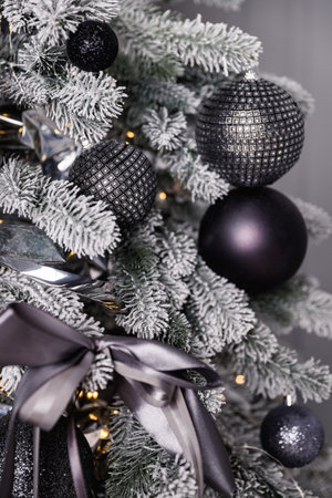 Black and silver Christmas balls on a snow-covered tree branch.の写真素材