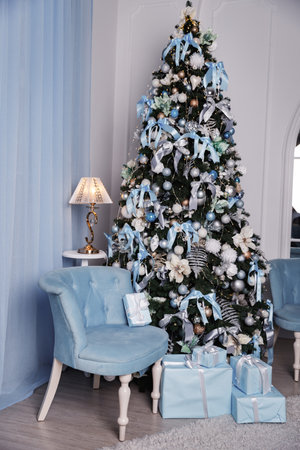 Christmas tree with blue armchair with packaged blue presents in a blue interior.の写真素材