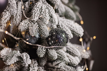 Black and silver Christmas balls on a snow-covered branch of a Christmas tree.の写真素材