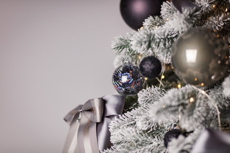 Black and silver Christmas balls on a snow-covered branch of a Christmas tree.の写真素材