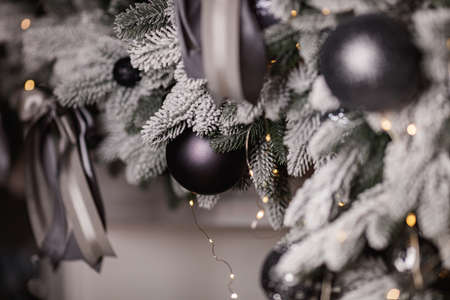 Black and silver Christmas balls on a snow-covered branch of a Christmas tree.の写真素材
