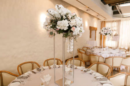 Festive Floral decor on wedding banquet tables in white colors with cutleryの写真素材
