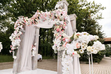 Wedding ceremony decorated with flowers and fabrics in light colors on the archの写真素材