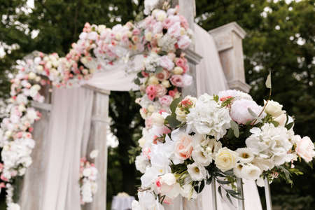 Wedding ceremony decorated with flowers and fabrics in light colors on the archの写真素材