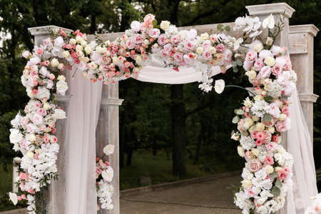 Wedding ceremony decorated with flowers and fabrics in light colors on the archの写真素材