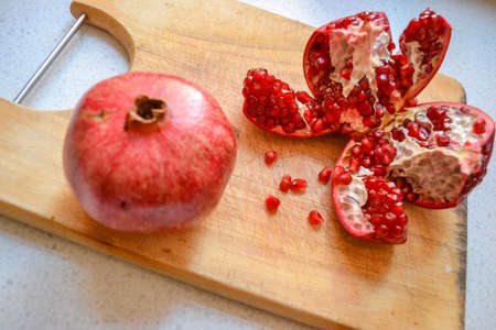 Red pomegranate torn into several pieces with berries falling nearbyの写真素材