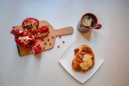 Pomegranate, croissant with almond nuts and lemon teaの写真素材