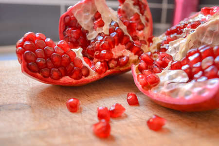 Red pomegranate torn into several pieces with berries falling nearbyの写真素材