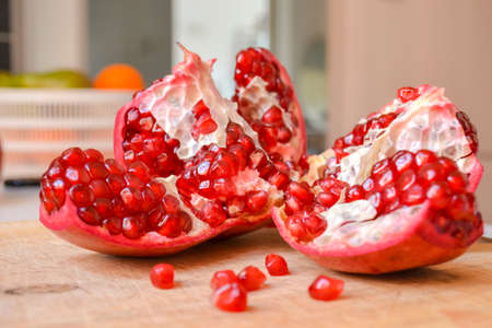 Red pomegranate torn into several pieces with berries falling nearbyの写真素材