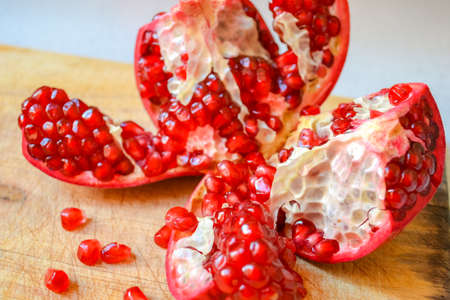 Red pomegranate torn into several pieces with berries falling nearbyの写真素材