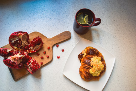 Pomegranate, croissant with almond nuts and lemon teaの写真素材