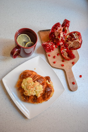 Pomegranate, croissant with almond nuts and lemon teaの写真素材