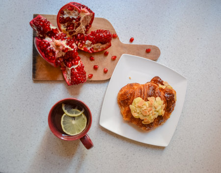 Pomegranate, croissant with almond nuts and lemon teaの写真素材