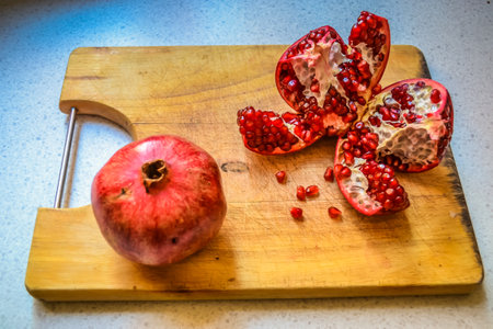 Red pomegranate torn into several pieces with berries falling nearbyの写真素材