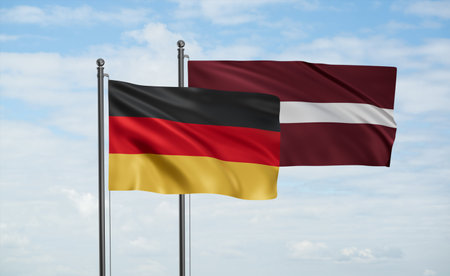 Latvia and Germany flag waving together in the wind on blue sky, two country cooperation conceptの写真素材