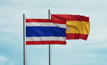 Spain and Thailand flag waving together in the wind on blue sky, two country cooperation conceptの写真素材